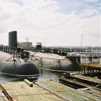 HMS Conqueror na základně, plavidlo napravo.
